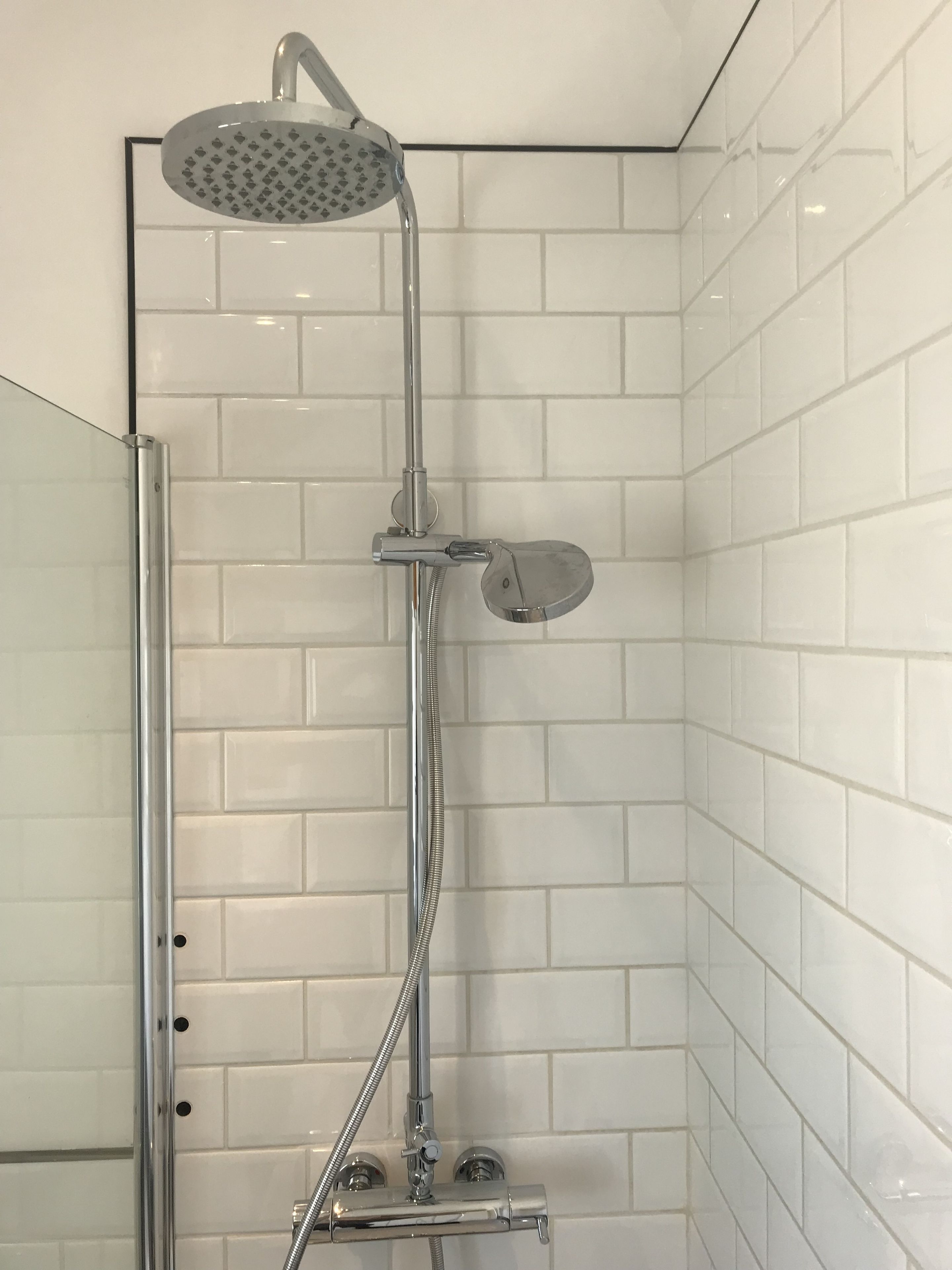 A shower with a handheld showerhead and a handheld shower attachment.