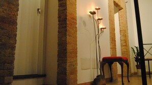 A room with exposed brick walls, a wooden ceiling, and a bench with a red cushion.