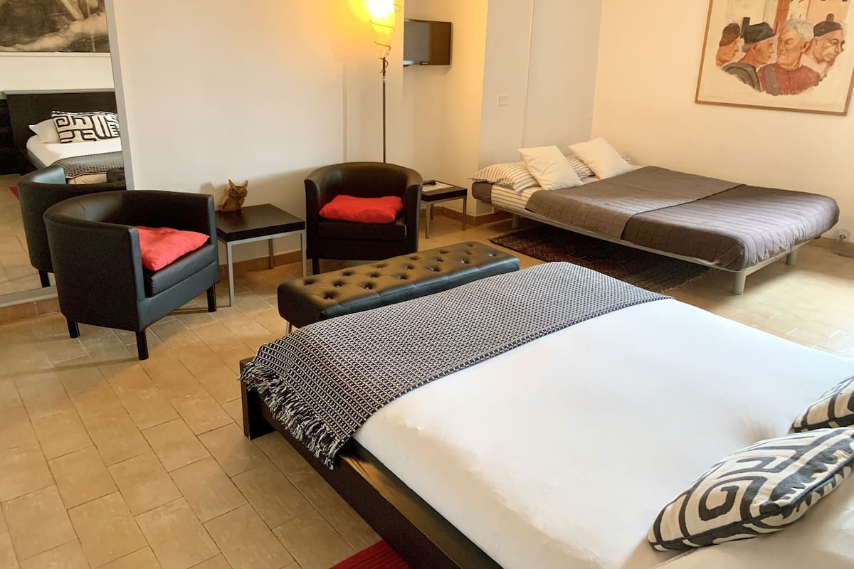 A hotel room with a bed, a chair, a small table, and a sofa.