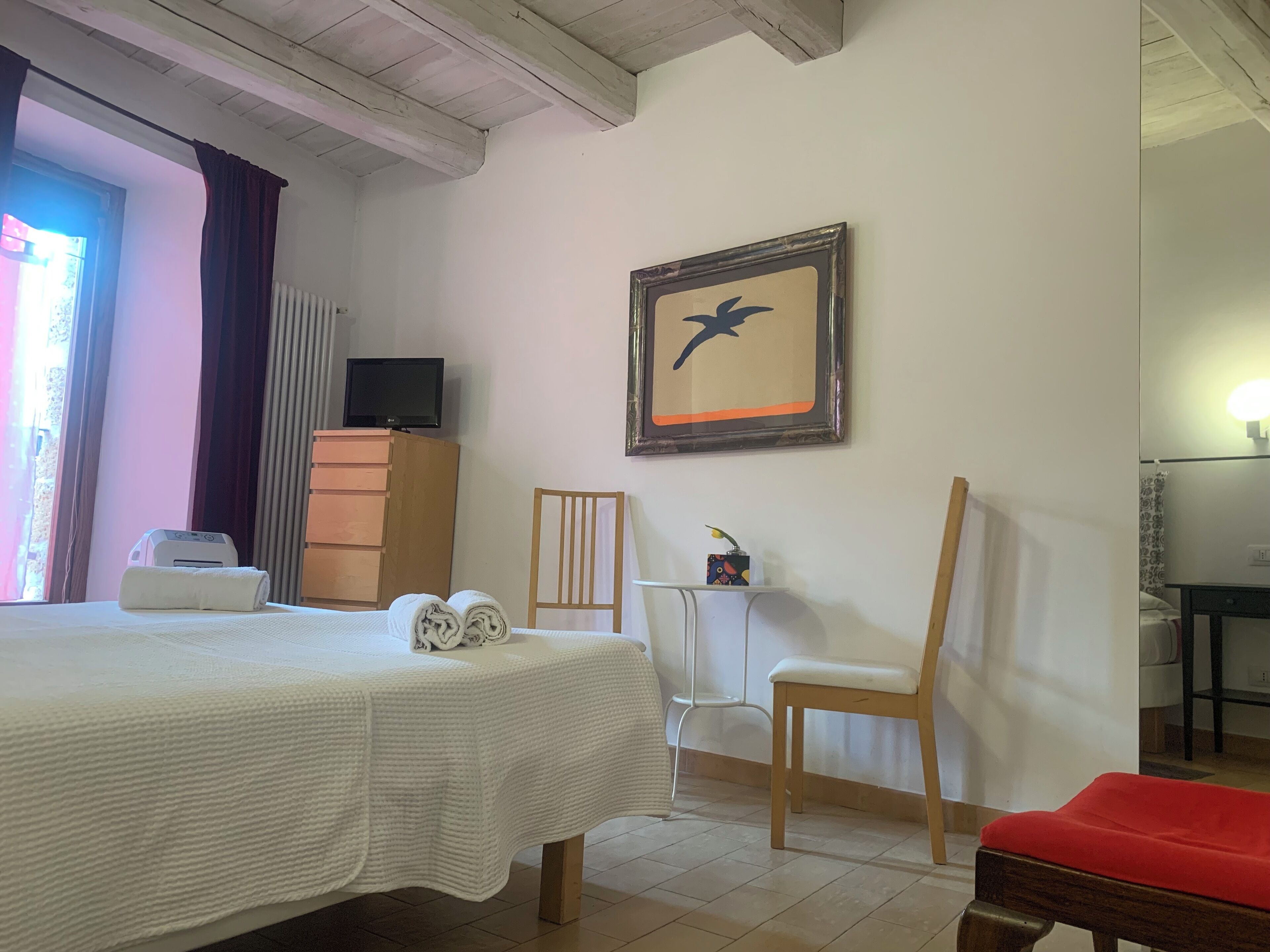 A hotel room with a bed, a television on a dresser, a framed picture on the wall, and a chair.