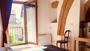 A bedroom with a bed, a desk, a chair, and a window with curtains.