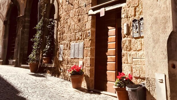 A historic stone building with arched doorways and a cobblestone street.