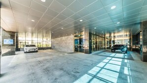 A modern building entrance with a covered parking area, glass doors, and a car parked inside. - Gimpo Pentastar Hotel (Gimpo)