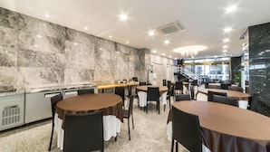A modern restaurant with marble walls, multiple dining tables, and a staircase leading to an upper level. - Gimpo Pentastar Hotel (Gimpo)