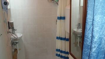 Un baño pequeño con inodoro, lavamanos y ducha.