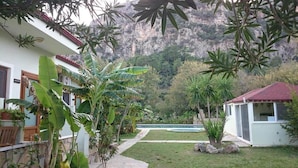 A garden with a swimming pool, a white building with a red roof, and a mountain backdrop. - Sirius Hotel (Ortaca)