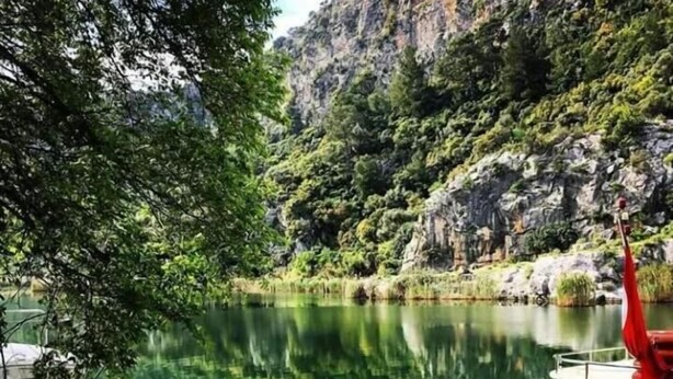 A serene lakeside setting with a wooden dock and a small boat with a red flag. - Sirius Hotel (Ortaca)