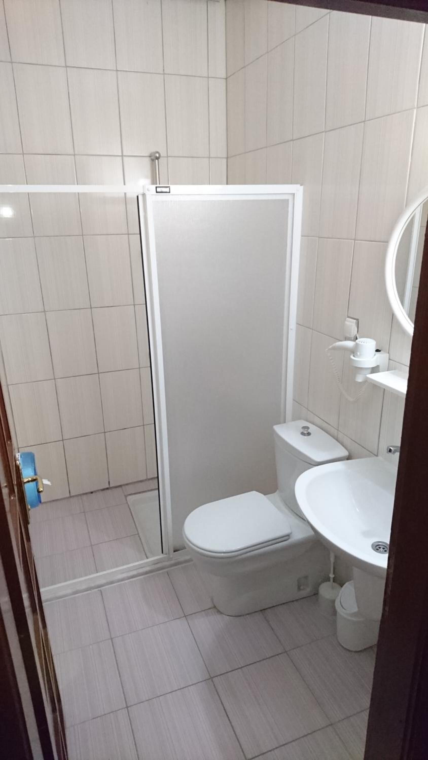 A bathroom with a toilet, sink, and shower stall.