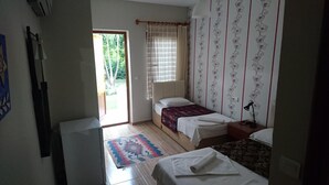 A small, well-lit bedroom with a single bed, a small table, and a window with curtains. - Sirius Hotel (Ortaca)