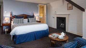 A bedroom with a bed, bedside tables, a fireplace, and a reading area with a table and chairs.