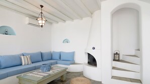 Un salon moderne avec un canapé bleu, une table basse en verre et une cheminée en pierre.