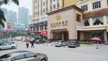 A hotel with a prominent sign in the center, surrounded by parked cars and a busy street.