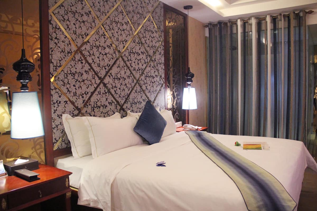 Habitación de hotel con una cama bien hecha, una mesita de noche con lámpara y un papel tapiz estampado.