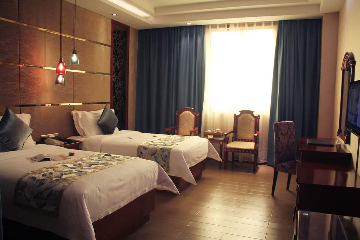 Una habitación de hotel con dos camas, un escritorio, una silla y un televisor.