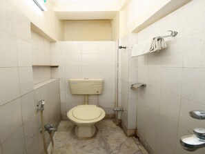 A small, tiled bathroom with a toilet, a towel rack, and a shower. - OYO 3301 Maya International (Kolkata)