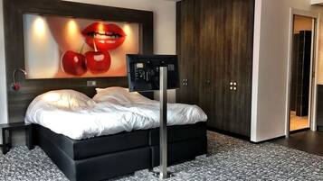 A modern bedroom with a large bed, a wall-mounted TV, and a wardrobe.