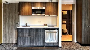 A modern kitchen with dark wood cabinets, stainless steel appliances, and a visible dishwasher. - Apart Food and Drinks (Zwolle)
