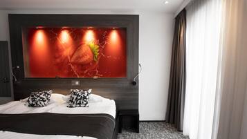 Habitación de hotel moderna con una cama grande, televisor montado en la pared y cabecera de madera oscura.