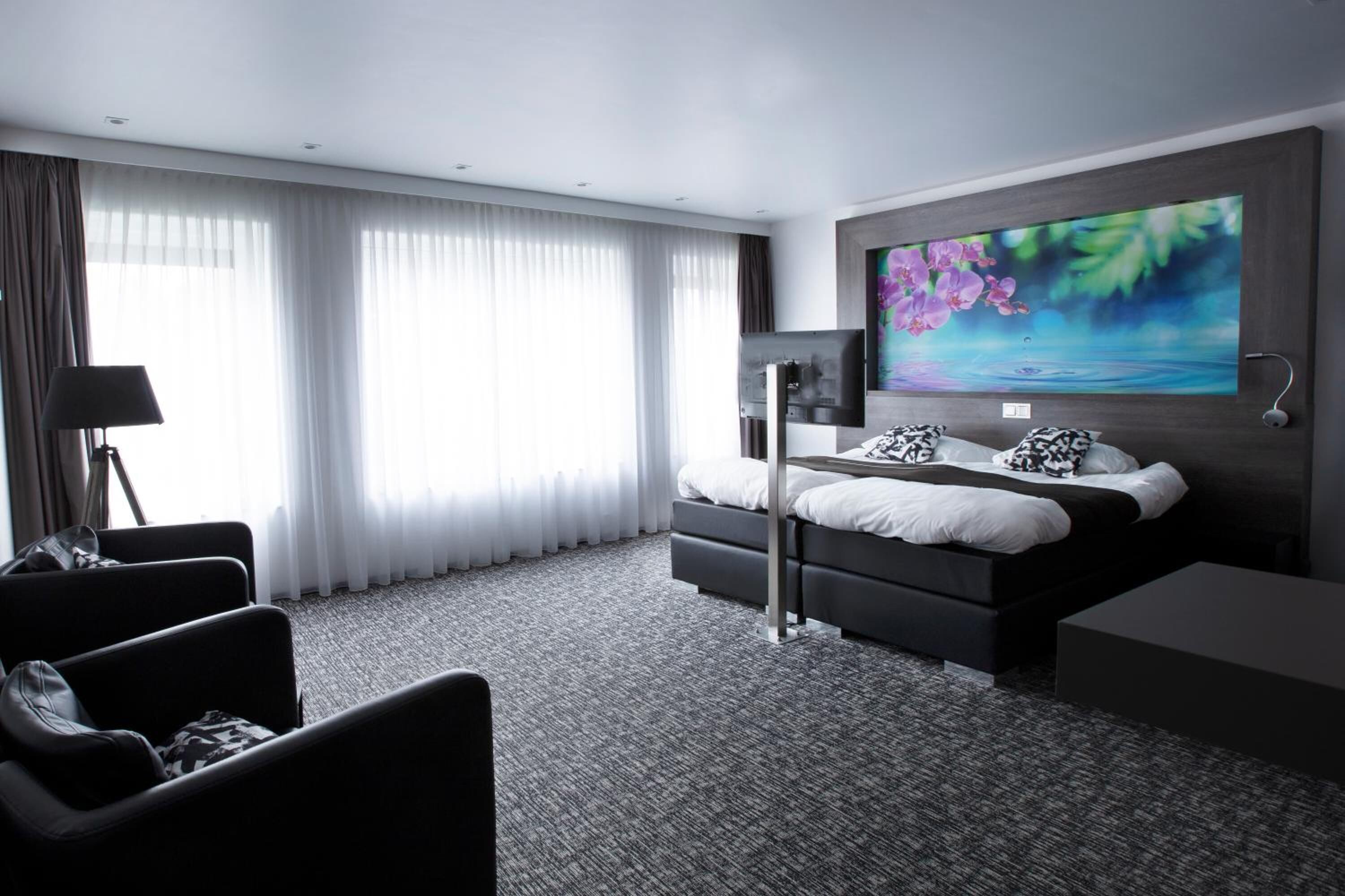 A modern hotel room with a large bed, a desk, and a TV.