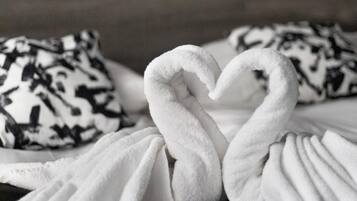Una cama con un cojín de estampado blanco y negro y una toalla blanca dispuesta en forma de cisne.