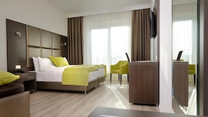 Ein modernes Hotelzimmer mit Bett, Schreibtisch, Sessel und Fernseher.