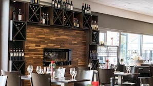 Ein Restaurant mit Holzwand, Weinkühlschränken und gedeckten Tischen.