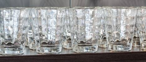 Una hilera de vasos transparentes y con textura sobre un estante de madera.