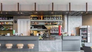 A modern bar area with a marble countertop, stools, and a variety of bottles and glasses. - Lake Como Golf Hotel (Carimate)