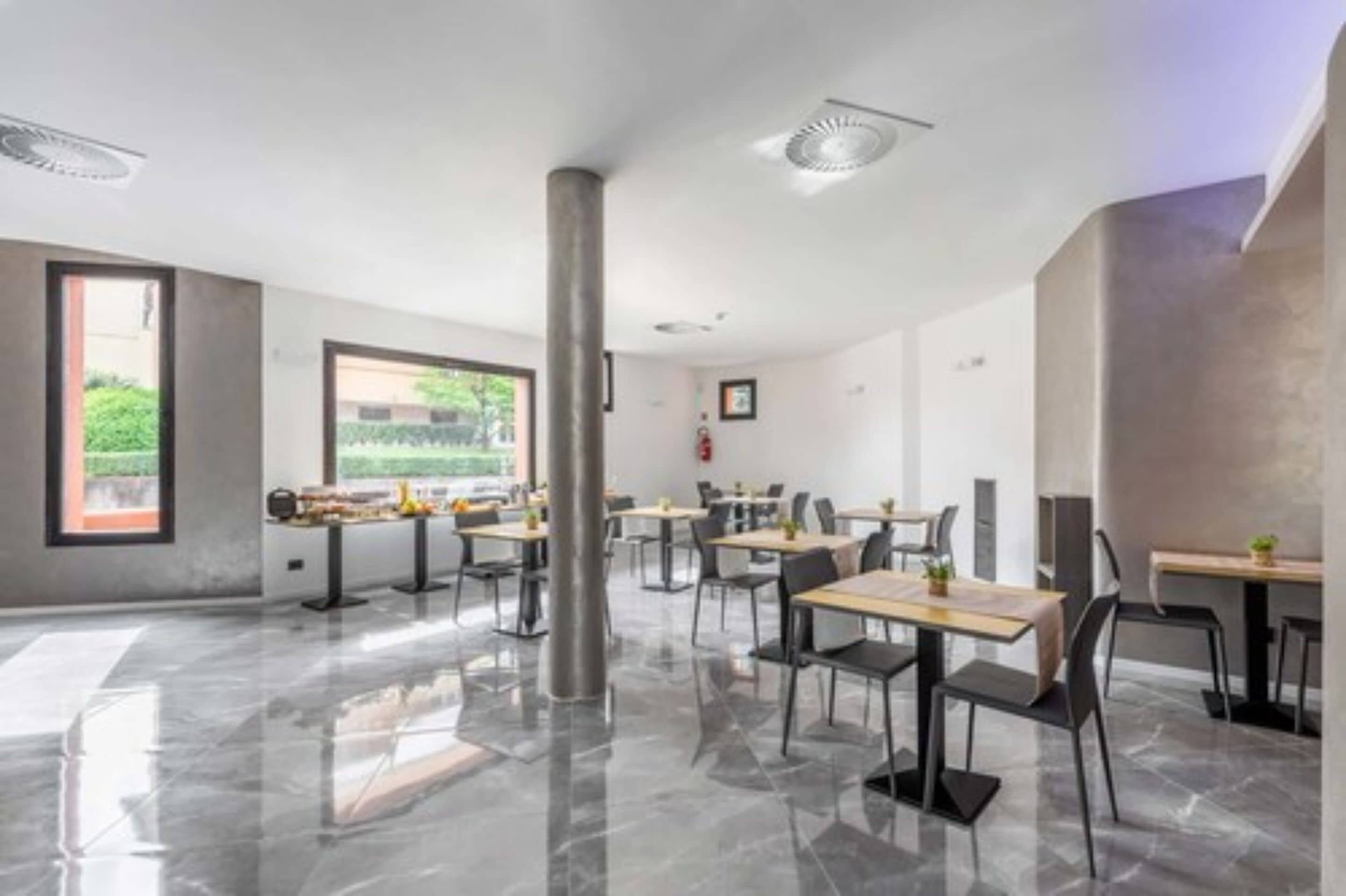 Un'area pranzo moderna con pavimento in marmo lucido, arredamento contemporaneo e ampie finestre con vista su del verde.