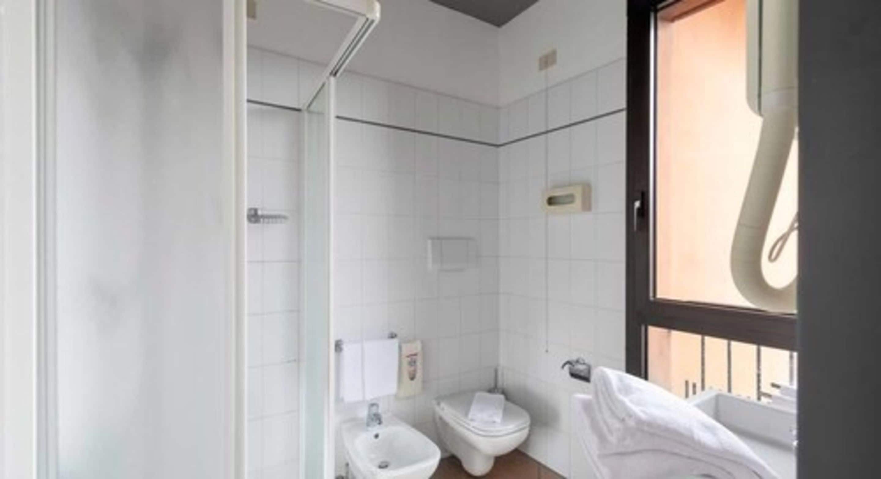 A bathroom with a bidet, toilet, and a towel rack.