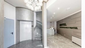 A modern hotel lobby with a marble floor, a staircase, and a reception desk. - Lake Como Golf Hotel (Carimate)