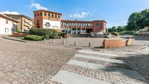 A modern building with a central entrance, paved pathways, and surrounding greenery. - Lake Como Golf Hotel (Carimate)