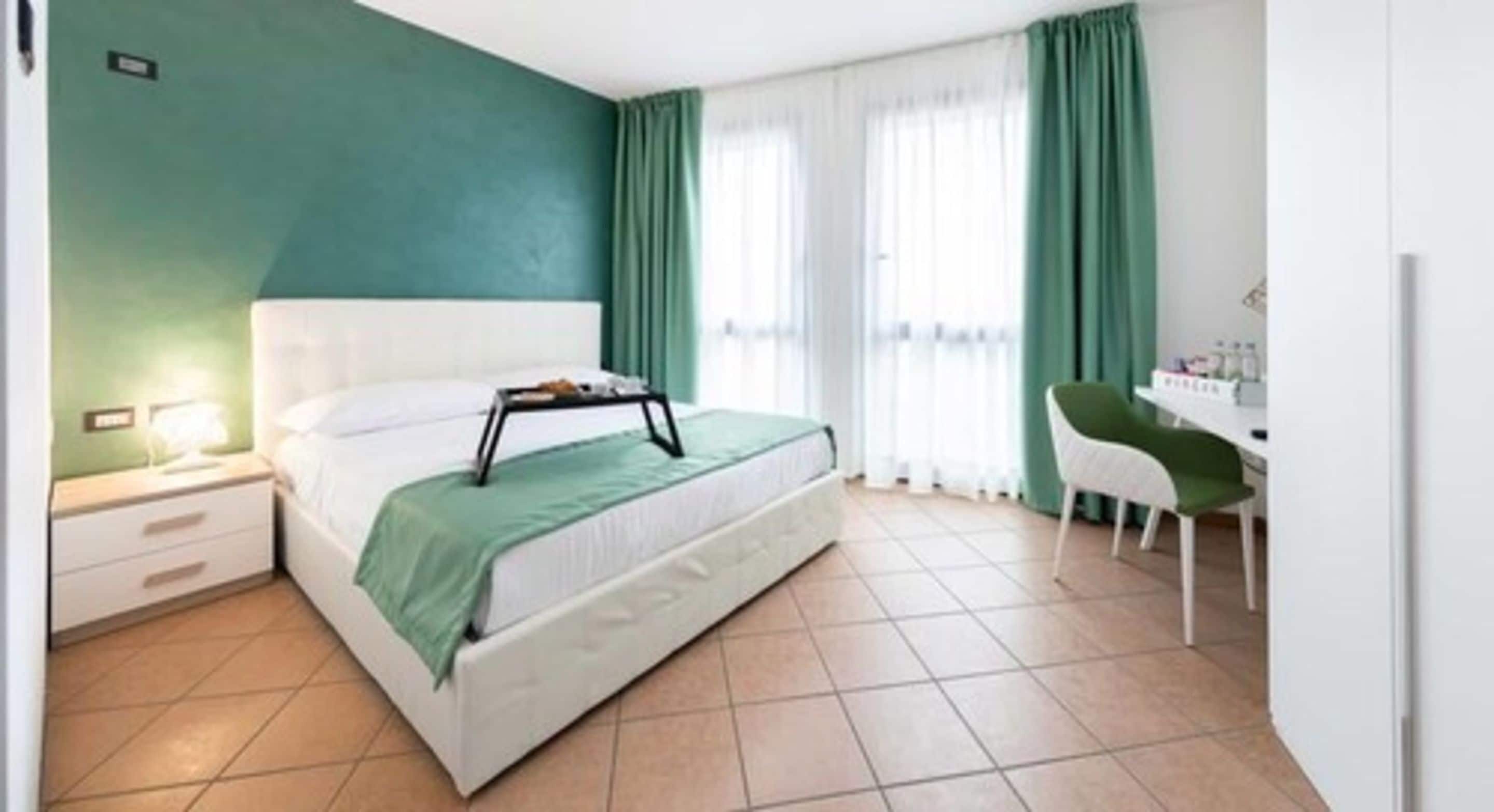 A bedroom with a bed, a nightstand, a desk, and a chair.