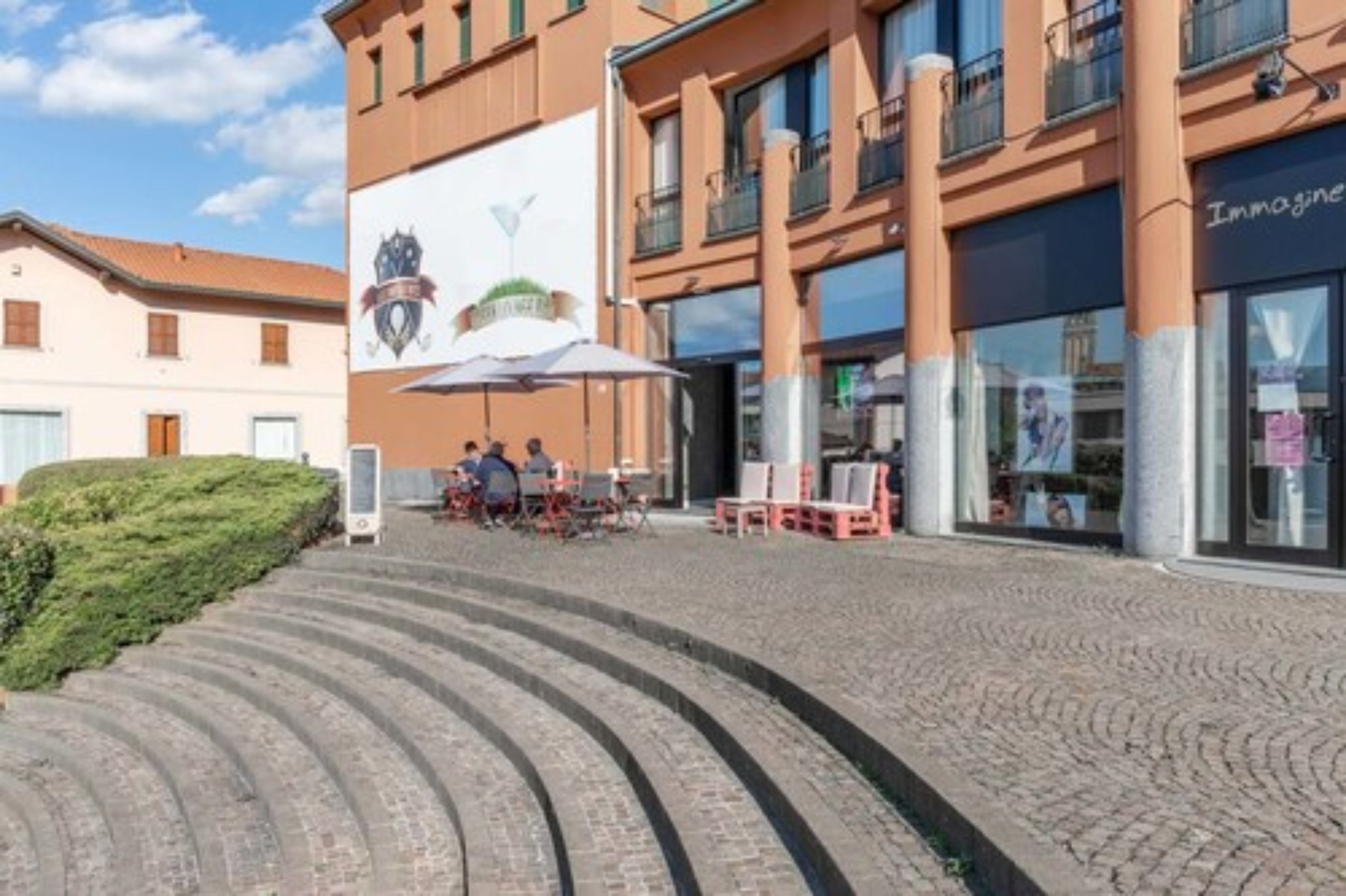 A building with a large mural, outdoor seating, and a staircase leading to the entrance.
