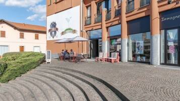 A building with a large mural, outdoor seating, and a staircase leading to the entrance.