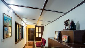 A hallway with a wooden reception desk, a red chair, framed pictures, and a bookcase filled with books.
