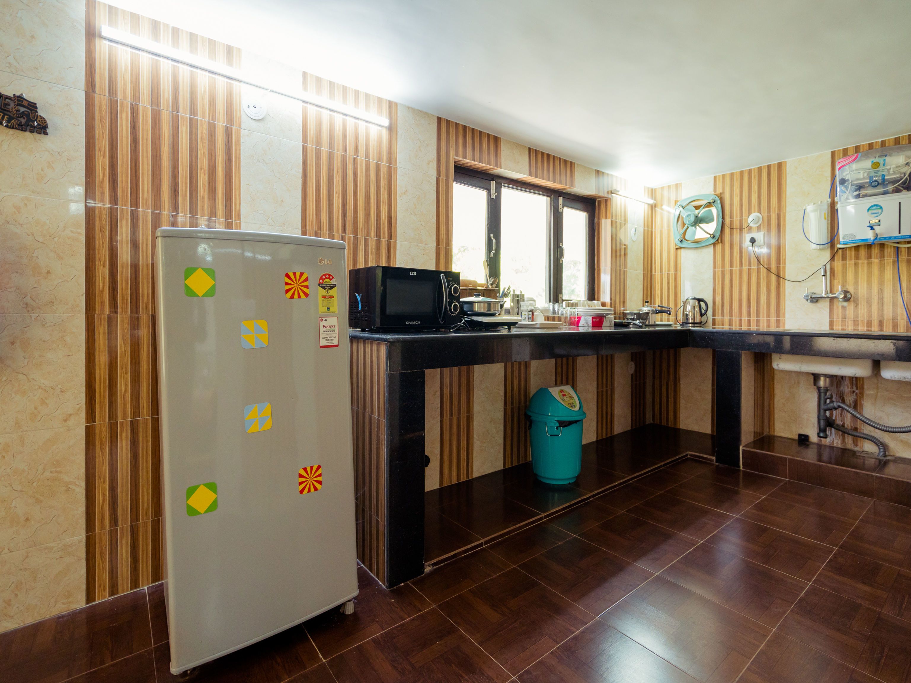 Una cocina equipada con refrigerador, microondas, lavamanos y salpicadero de azulejos.