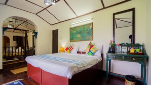 A bedroom with a bed, a nightstand, a mirror, a door, and a wall with a decorative piece.