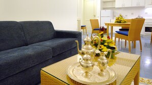 Una sala de estar con un sofá, una mesa de comedor con sillas y una cocina al fondo.