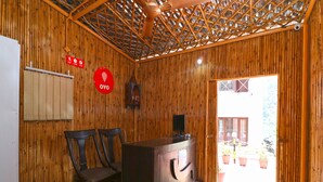 A reception area with a wooden interior, a reception desk, two chairs, a television, and a door leading outside. - OYO 13756 Damyanty Residency & Resort (Nainital)