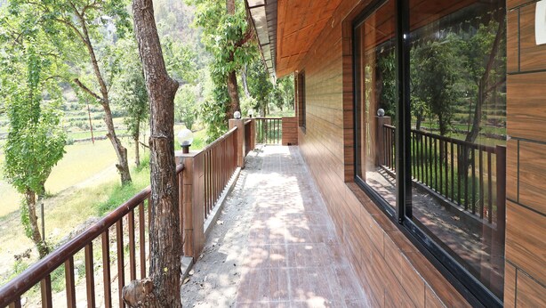 A wooden balcony with a view of a lush green landscape. - OYO 13756 Damyanty Residency & Resort (Nainital)