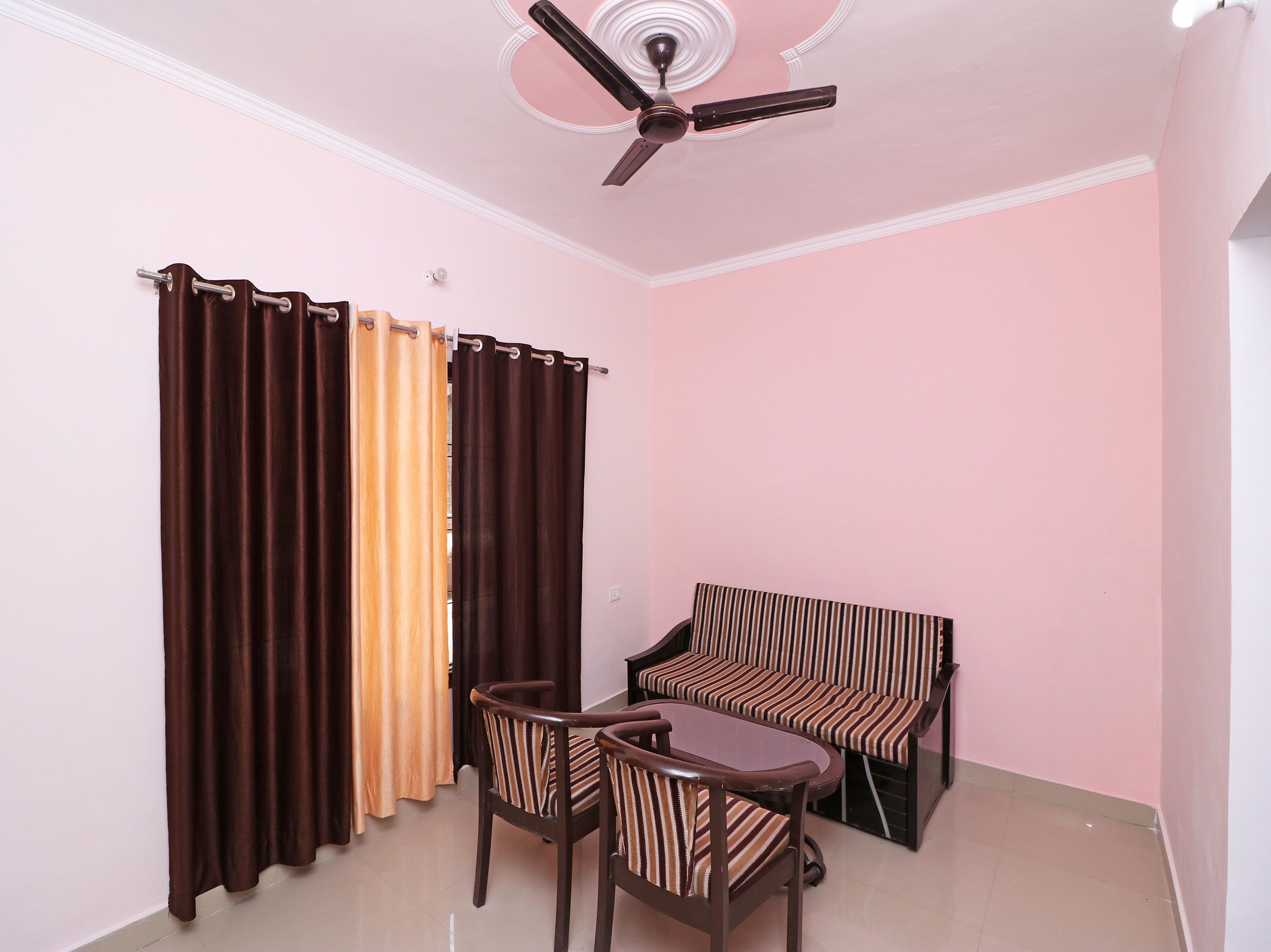 A room with a ceiling fan, a sofa, two chairs, and a table.
