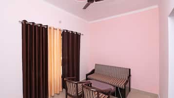 A room with a ceiling fan, a sofa, two chairs, and a table.