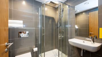 A modern bathroom with a glass-enclosed shower, a white sink, and a mirror.