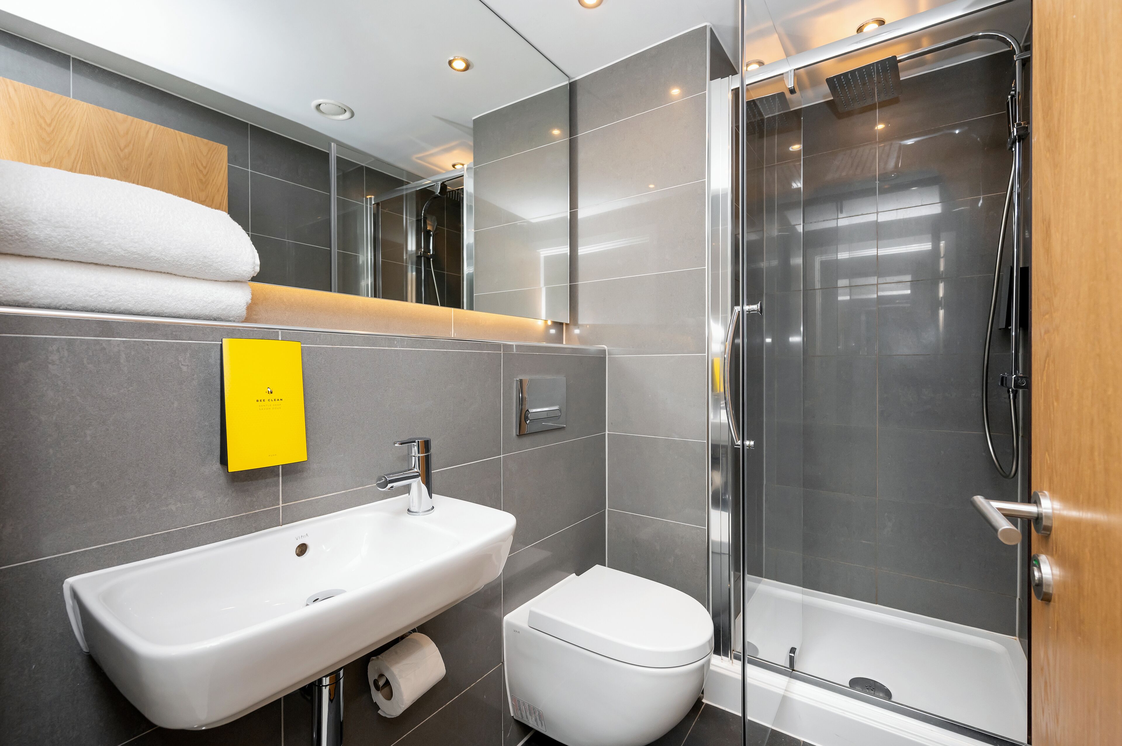 Une salle de bain moderne avec un lavabo blanc, des toilettes et une douche à parois de verre.