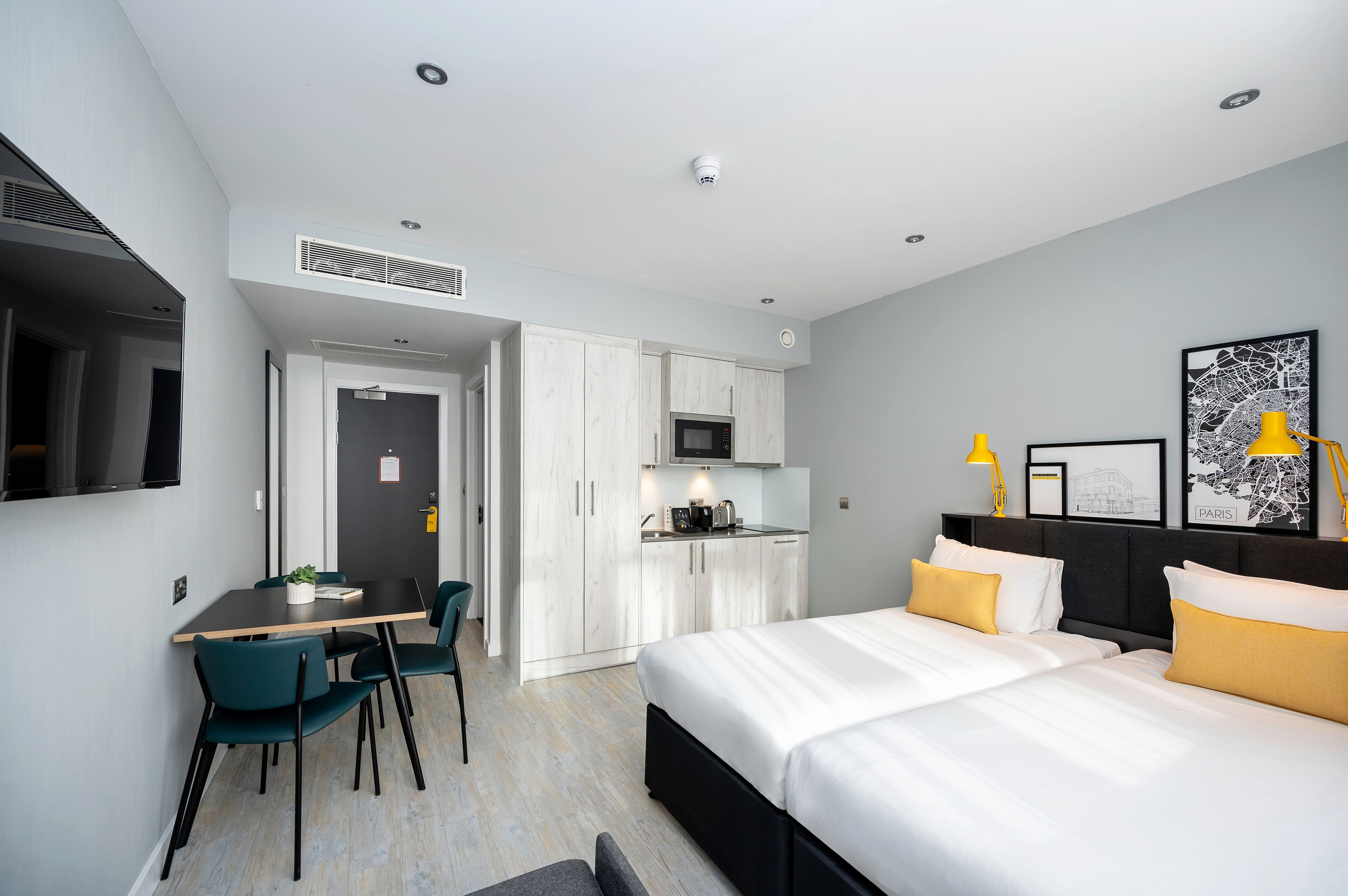 Een moderne hotelkamer met een bed, nachtkastje en een bureau met stoelen.