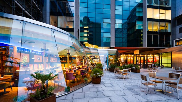 An outdoor café with seating and potted plants, surrounded by modern buildings. - Staycity Aparthotels, Liverpool, Waterfront (Liverpool)