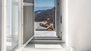 Een badkamer met een groot raam dat uitkomt op een balkon, een wastafel en een handdoekhouder.