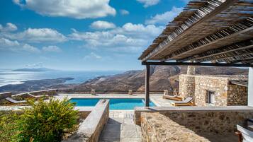 Uma área de piscina com vista para o mar e montanhas.