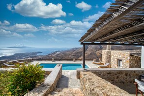 Un espace piscine offrant une vue sur la mer et les montagnes.